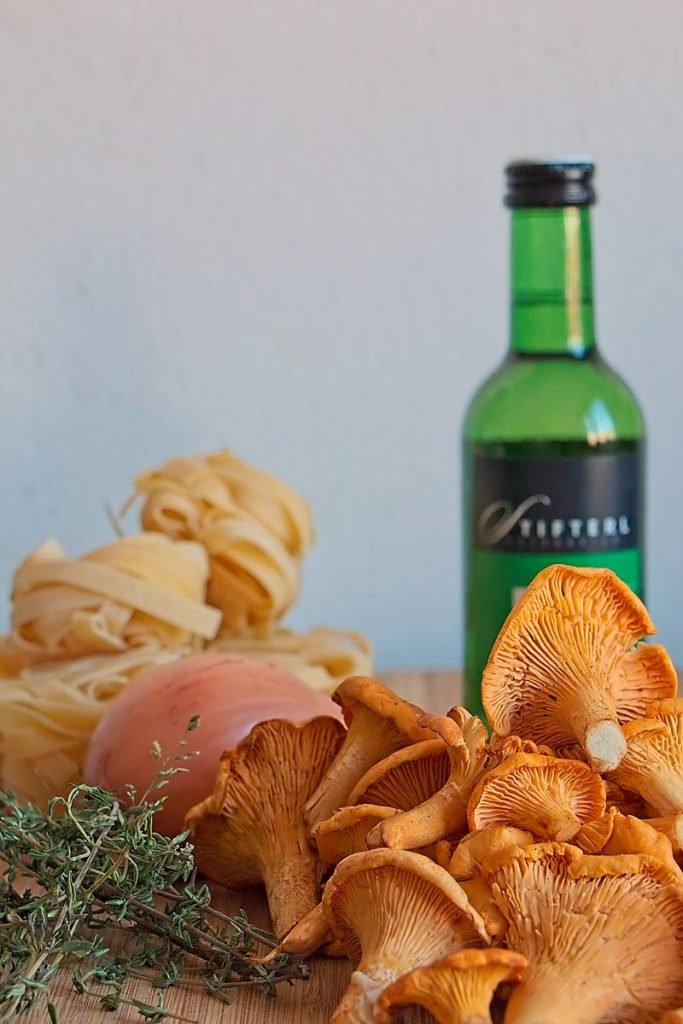 Ingredients for chanterelle tagliatelle: fresh chanterelles, tagliatelle pasta, onion, thyme, olive oil, and white wine