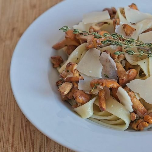 Chanterelle tagliatelle pasta served in a bowl with fresh thyme and Parmesan