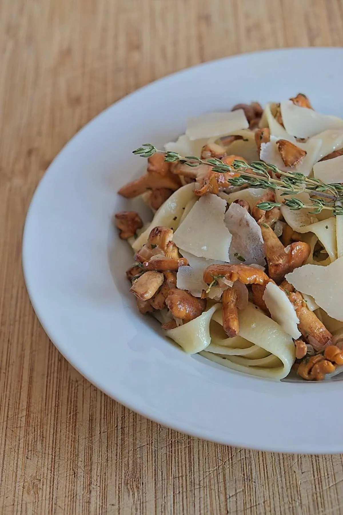 Chanterelle tagliatelle pasta served in a bowl with fresh thyme and Parmesan