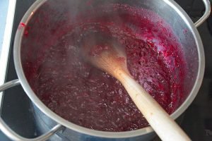 Lingonberry apple jam bubbling and thickening during cooking.