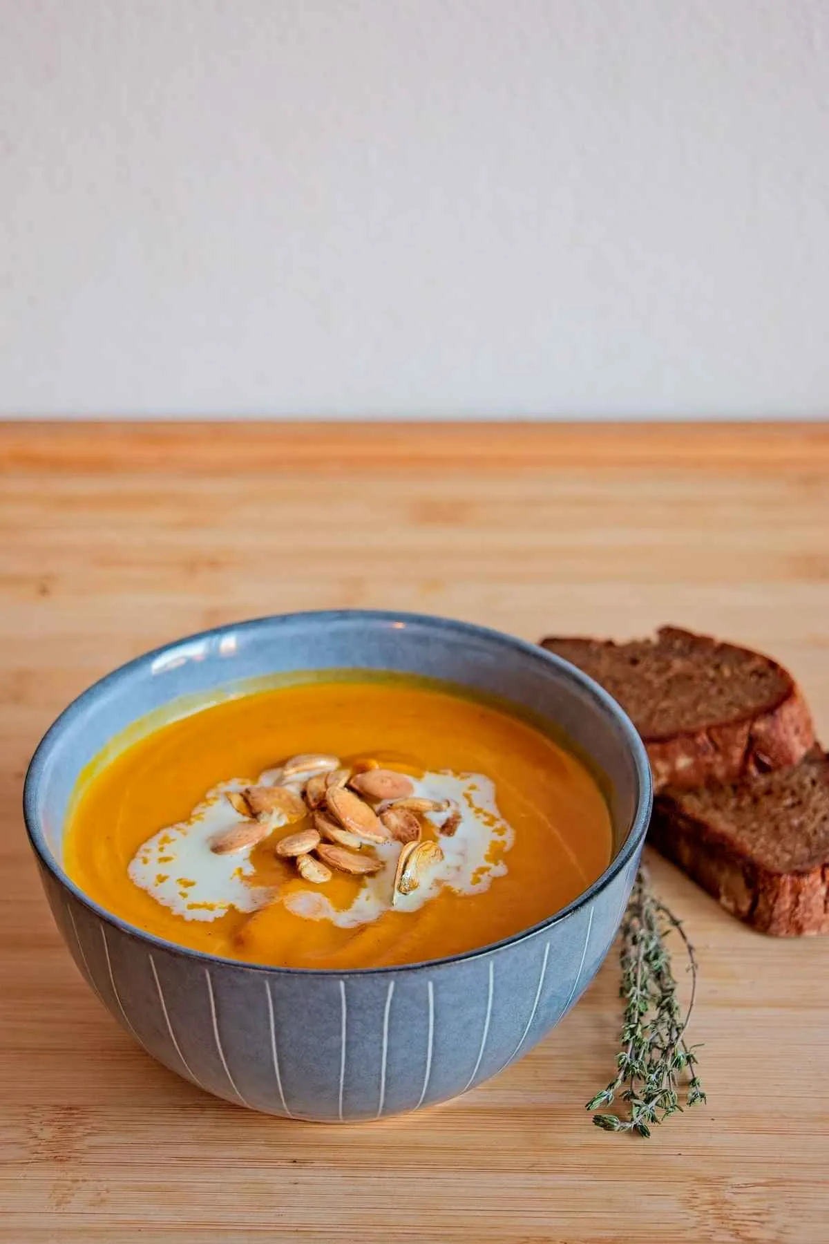 Bowl of honey roasted pumpkin soup with cream, roasted seeds, and bread