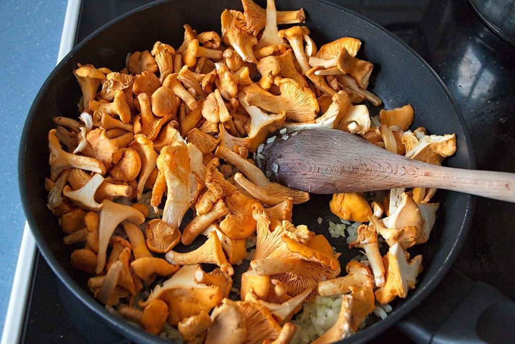 Chanterelles added to sautéed onions in a pan