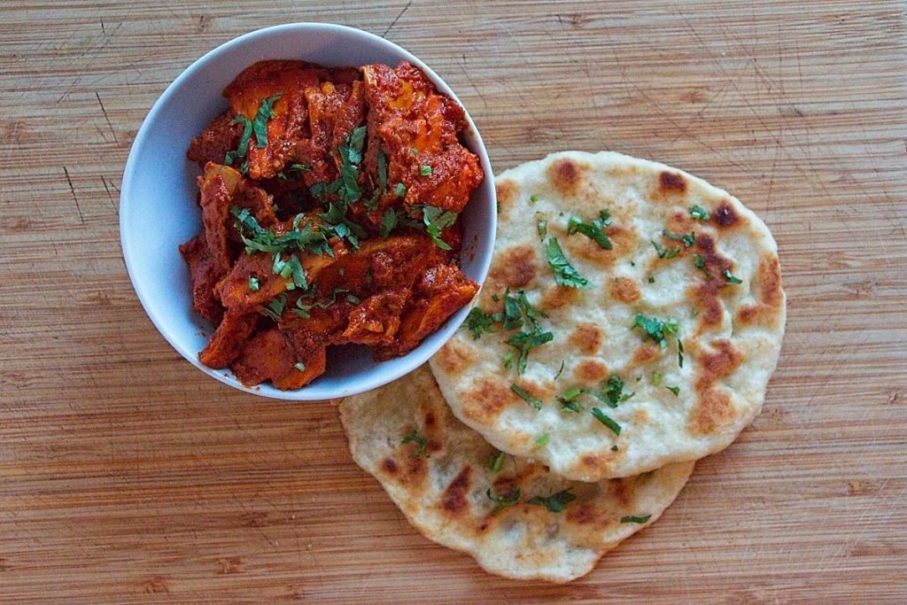 Chicken of the woods butter chicken served with fresh naan bread and coriander garnish