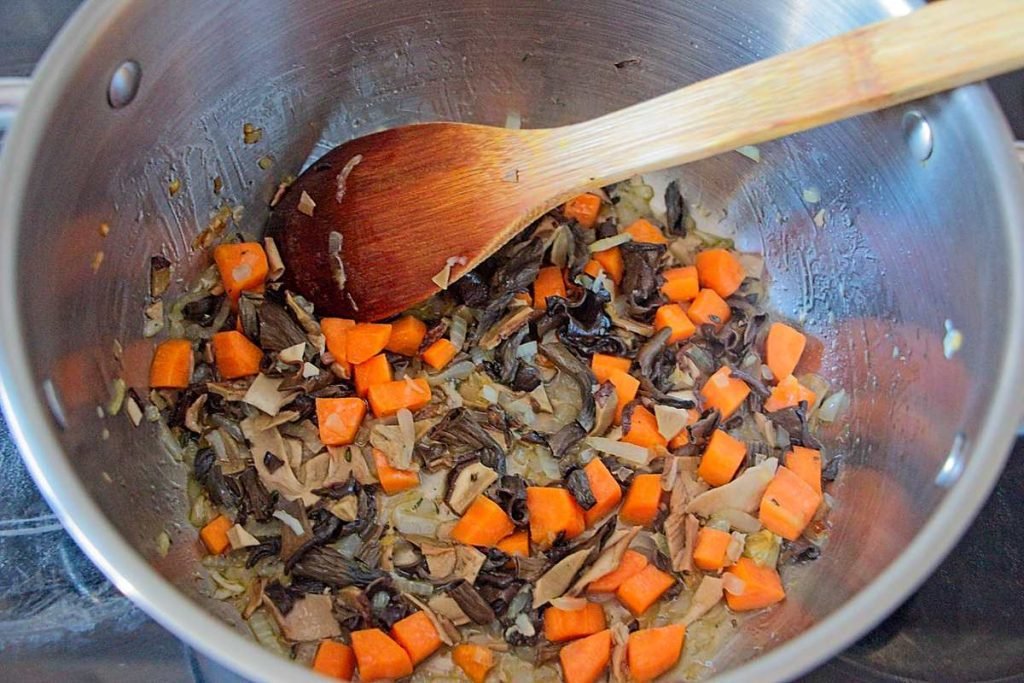 Onions, carrots, and rehydrated mushrooms cooking in a pot as the soup base