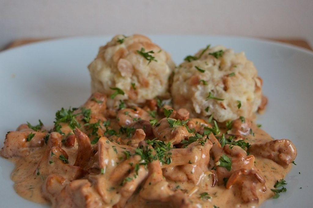 Creamy chanterelle sauce with bread dumplings and parsley garnish on a plate