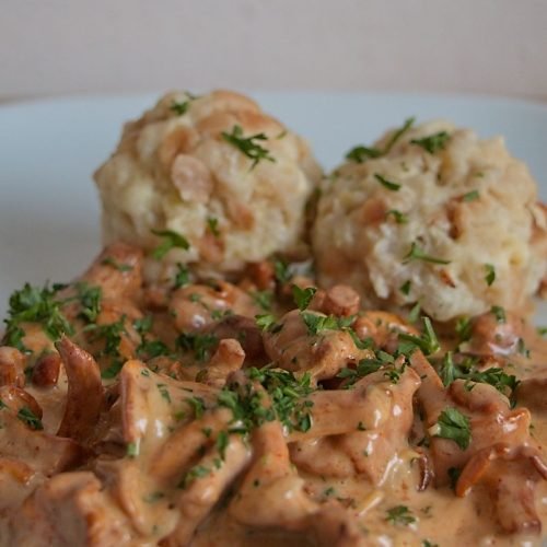 Creamy chanterelle sauce with bread dumplings and parsley garnish on a plate