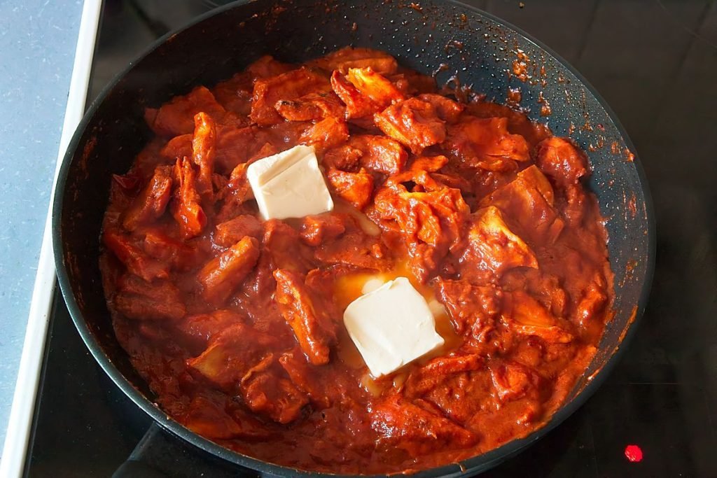 Creamy chicken of the woods butter chicken with vegan butter melting into the tomato curry sauce