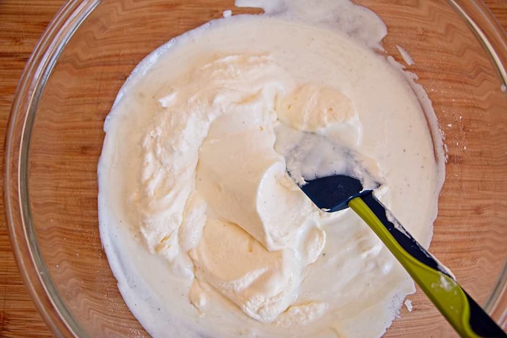 Folding whipped cream into the yogurt mixture with a spatula.