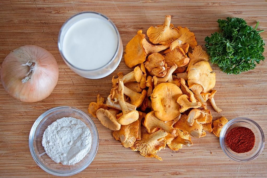 Ingredients for creamy chanterelle sauce with fresh chanterelles, onion, cream, parsley, flour, and paprika