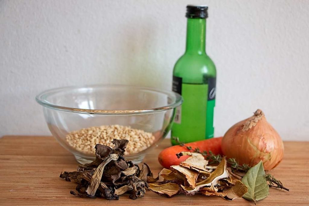 Ingredients for wheat berry and wild mushroom soup including wheat berries, dried mushrooms, onion, carrot, and white wine