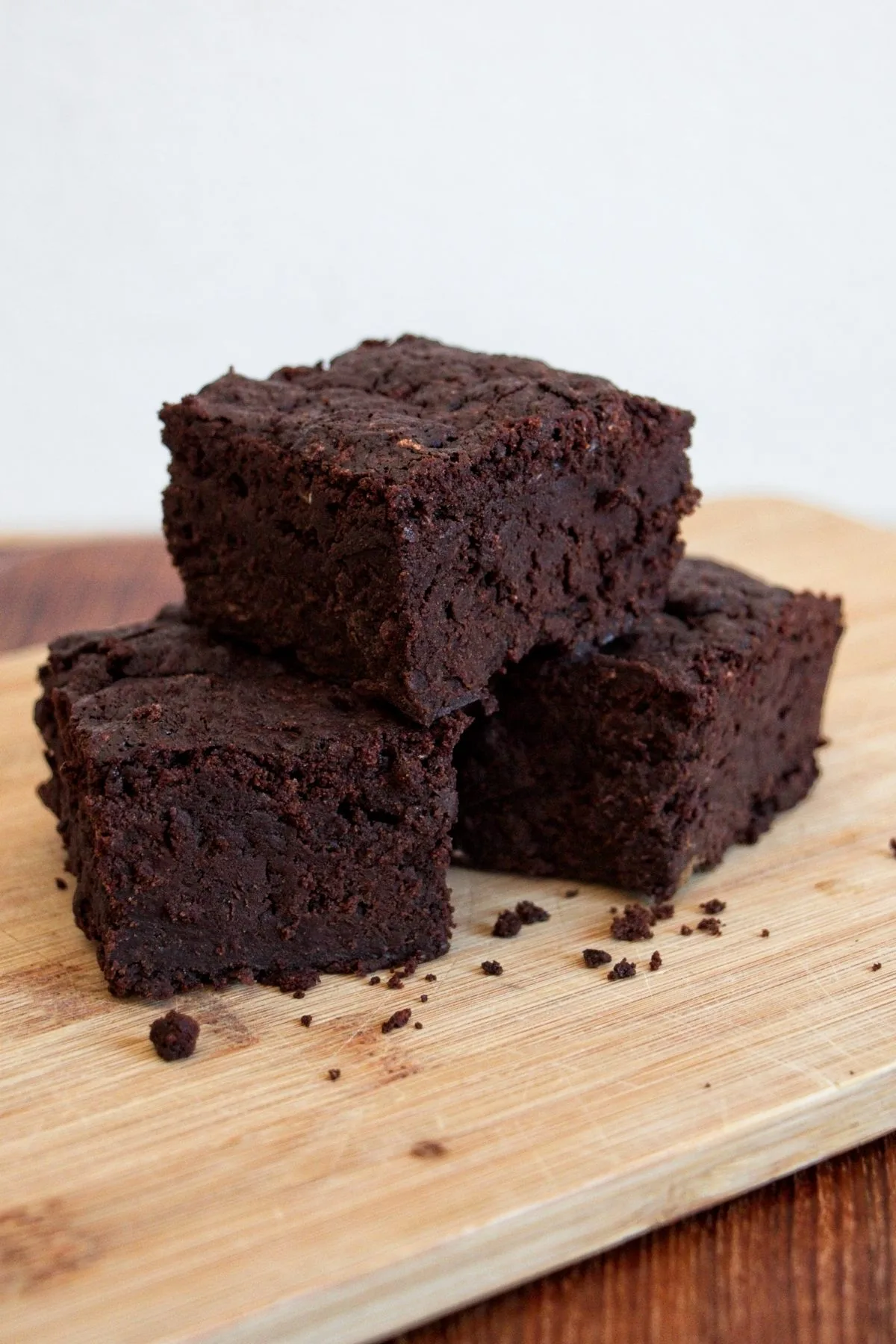 Stack of fudgy vegan tromboncino squash brownies on a wooden board.