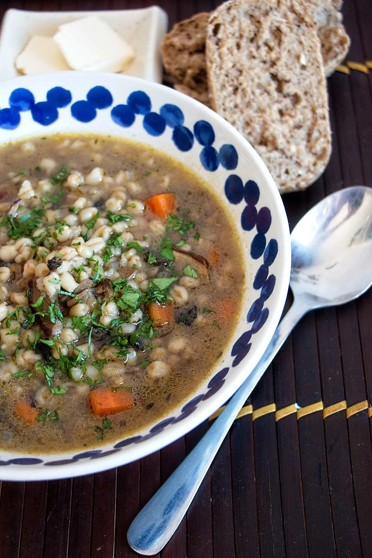 Wheat berry and wild mushroom soup served in a bowl with fresh parsley and bread