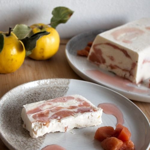 Slice of frozen quince terrine with yogurt and honey served on a plate with poached quince and syrup.