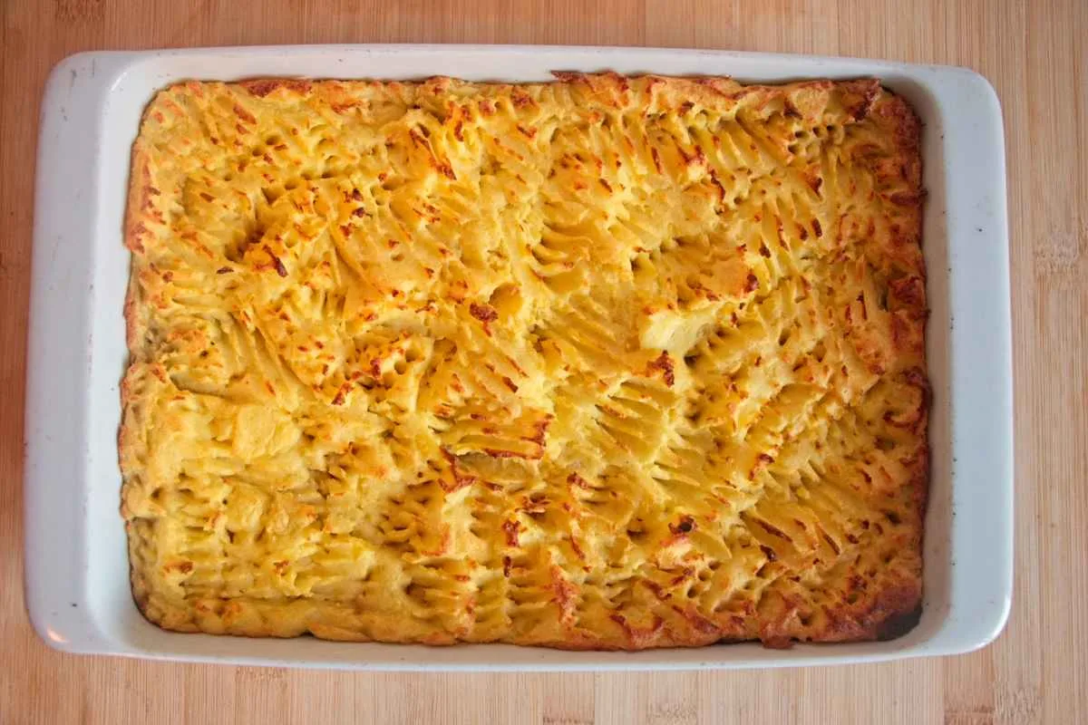 The baked vegetarian cottage pie with porcini in a white dish, showing the golden mashed potato topping.