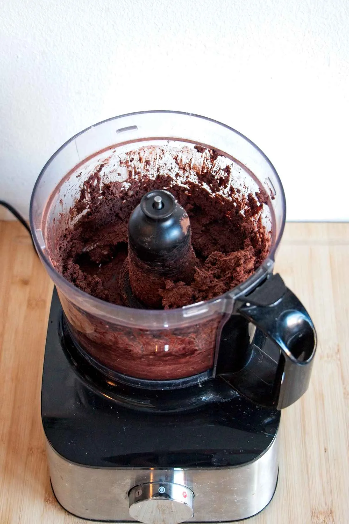 Blended chocolate and chestnut mixture inside a food processor on a wooden board.