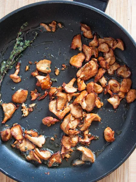 Golden sautéed wood hedgehog mushrooms in a pan with thyme.