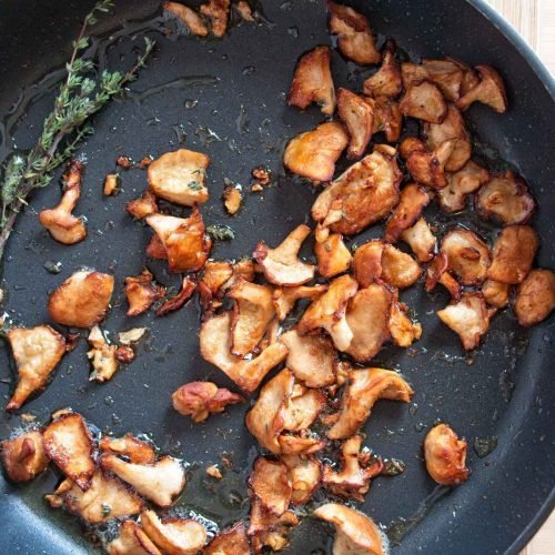 Golden sautéed wood hedgehog mushrooms in a pan with thyme.