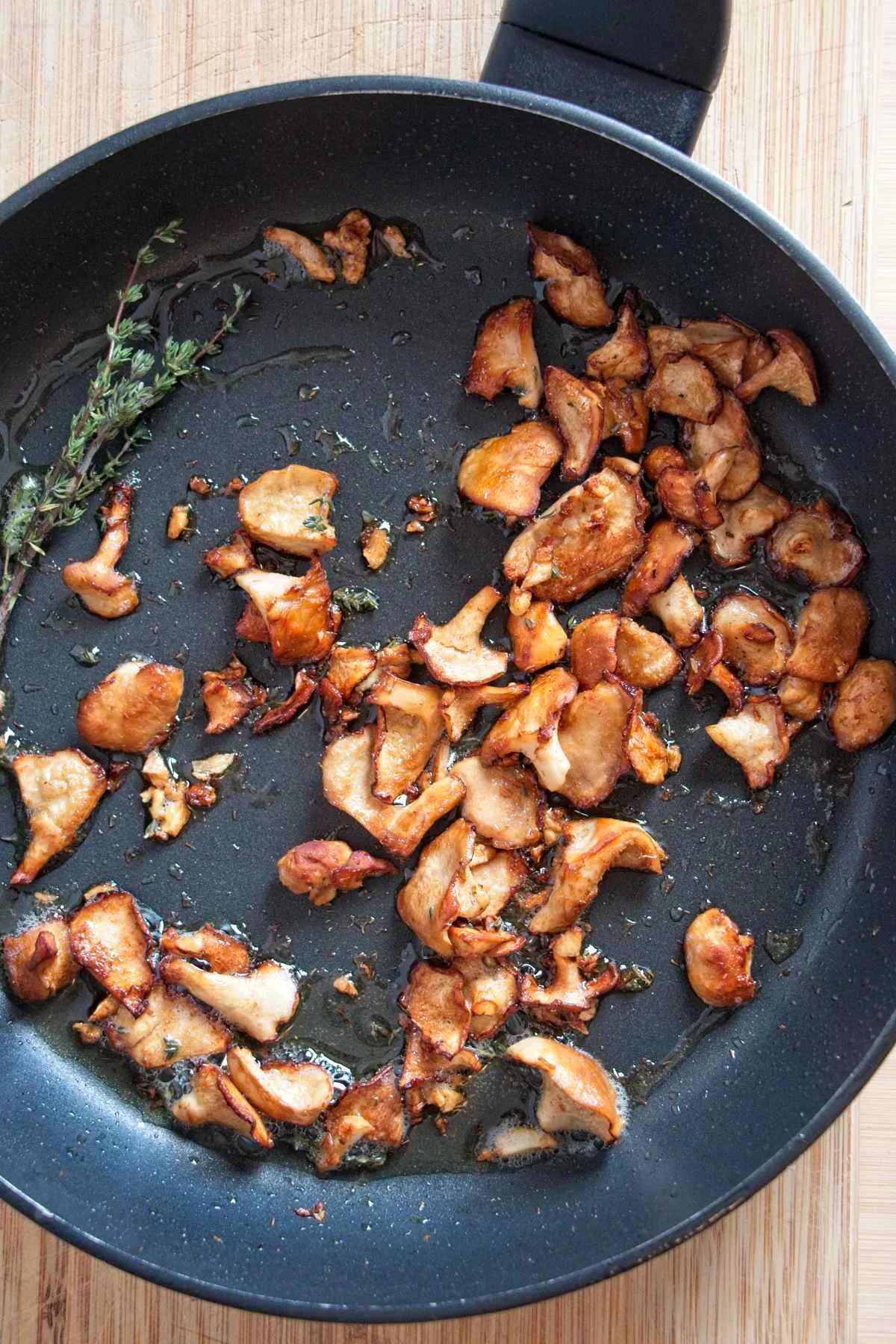 Golden sautéed wood hedgehog mushrooms in a pan with thyme.
