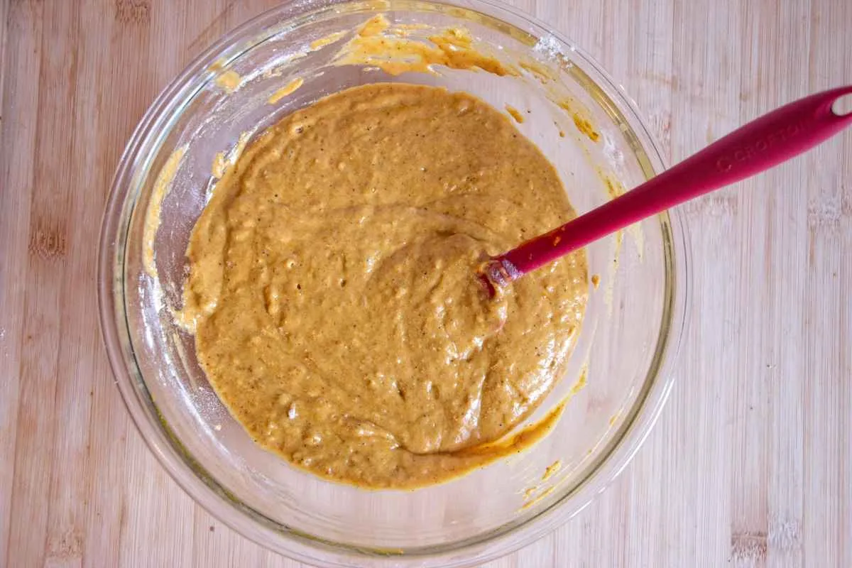Pumpkin loaf batter mixed in a large glass bowl with a spatula.