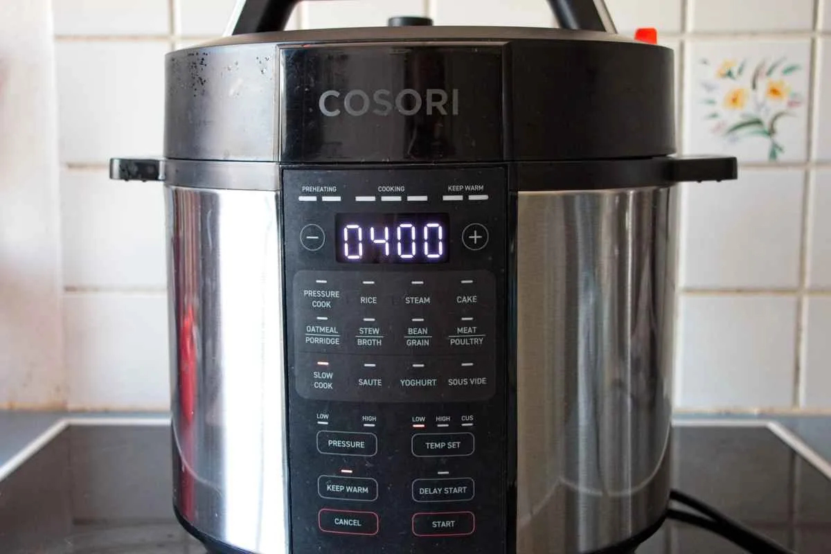 Electric pressure cooker set to a four-hour slow-cook cycle on a kitchen counter.