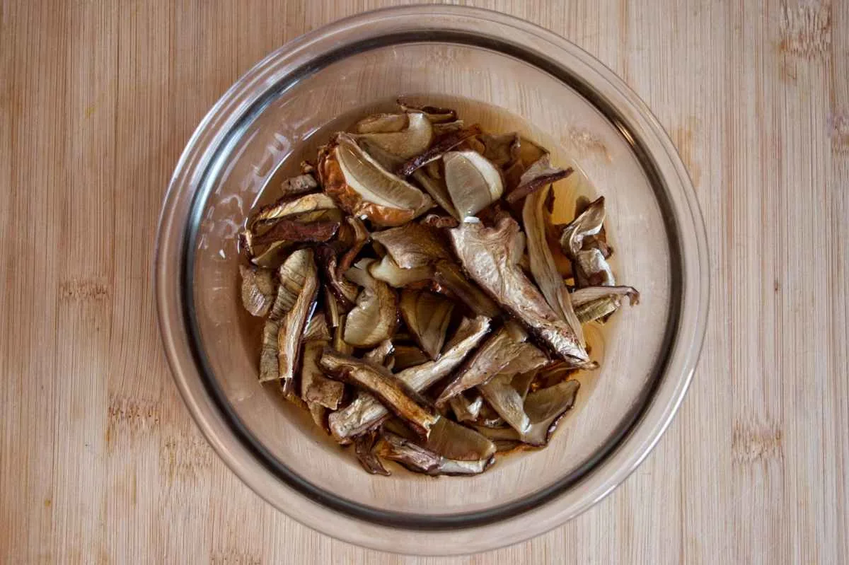 Rehydrated ceps sitting in their soaking liquid in a glass bowl.