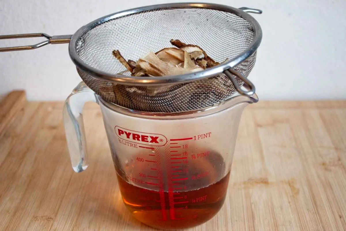 Straining the porcini soaking liquid through a fine mesh sieve.