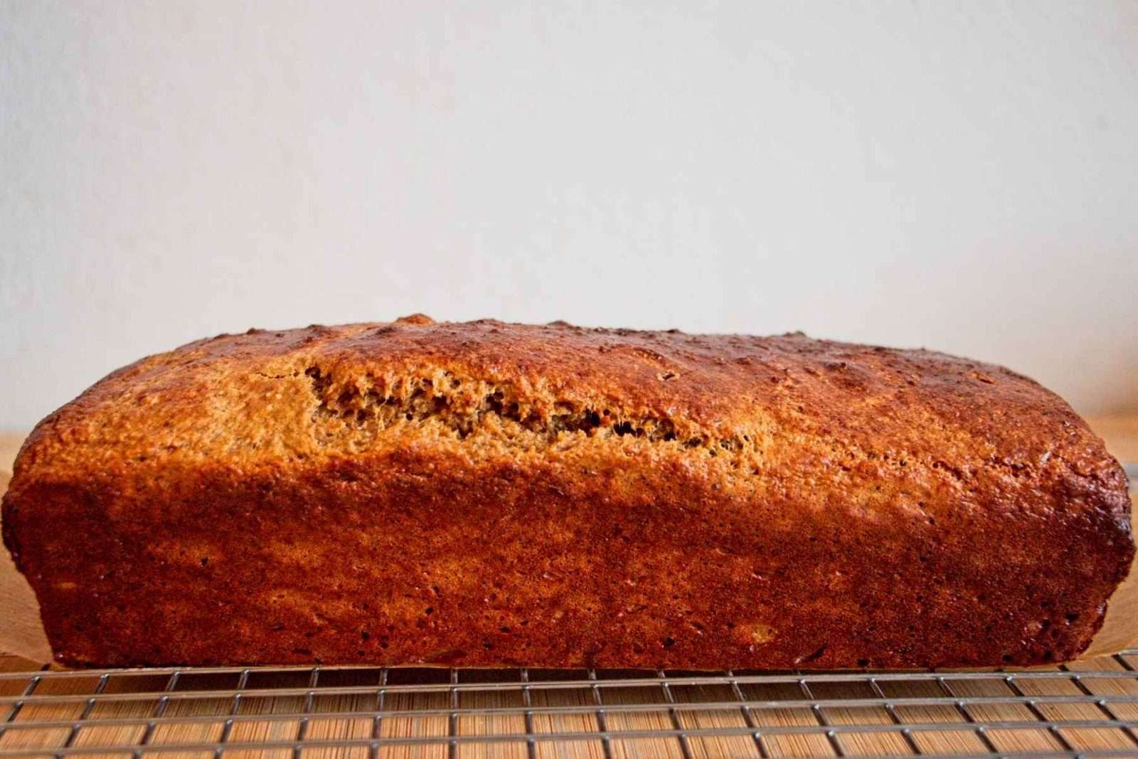 Whole baked protein banana bread loaf cooling on a wire rack.