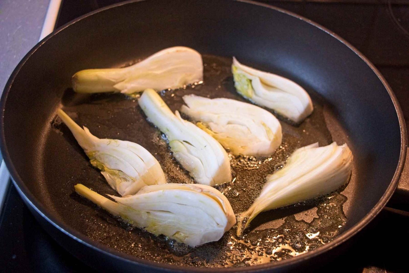 Fennel wedges cooking in a frying pan during the caramelising stage.