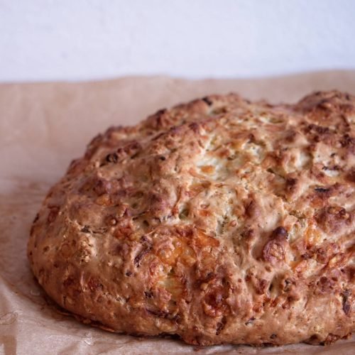 Freshly baked soda bread loaf with a deeply golden crust cooling on baking paper.