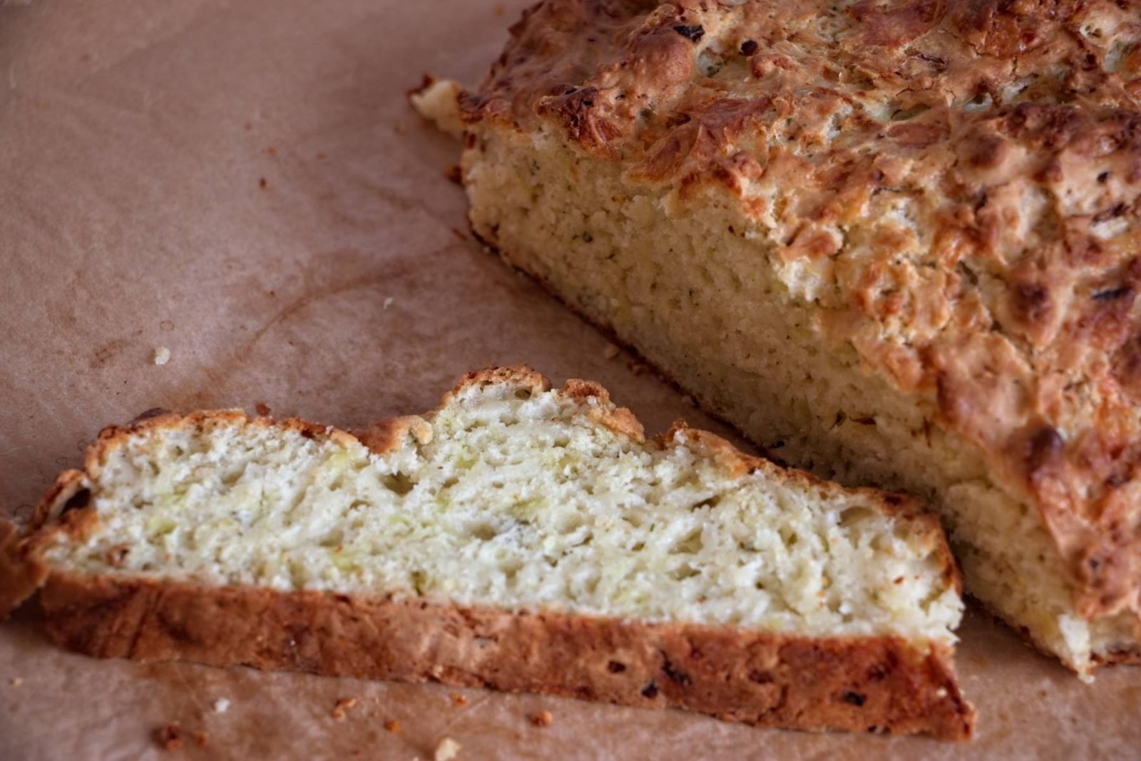 Close-up of cheddar onion soda bread crumb showing a soft interior beneath a golden crust.