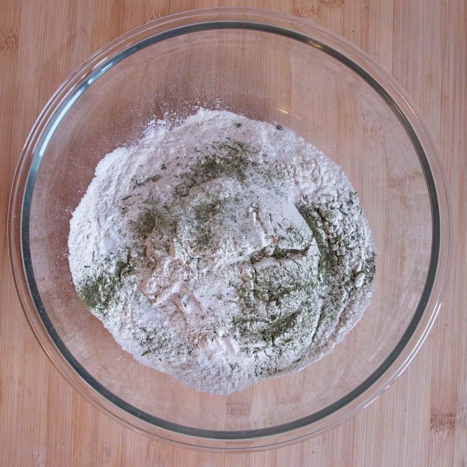 Flour, salt, bicarbonate of soda, and dried herbs mixed together in a bowl before adding the liquid.