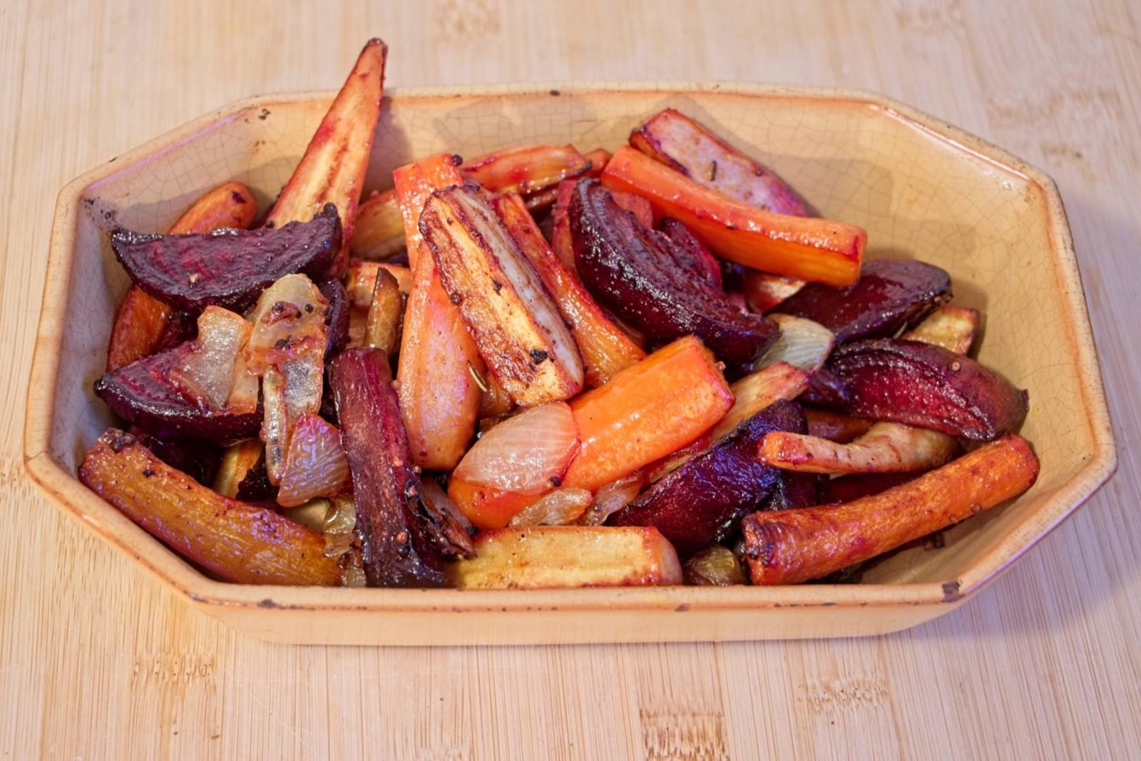 Honey mustard roasted root vegetables served in a rustic bowl, with carrots, parsnips, beetroot, and caramelised onions