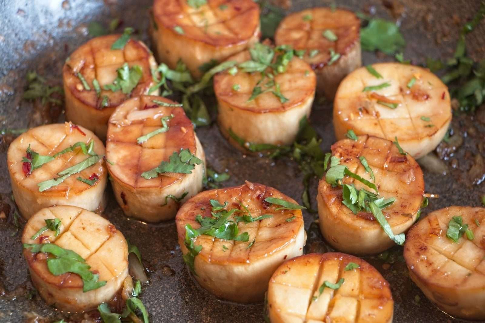Golden king oyster mushroom scallops coated in a glossy lemongrass butter sauce and sprinkled with fresh herbs.