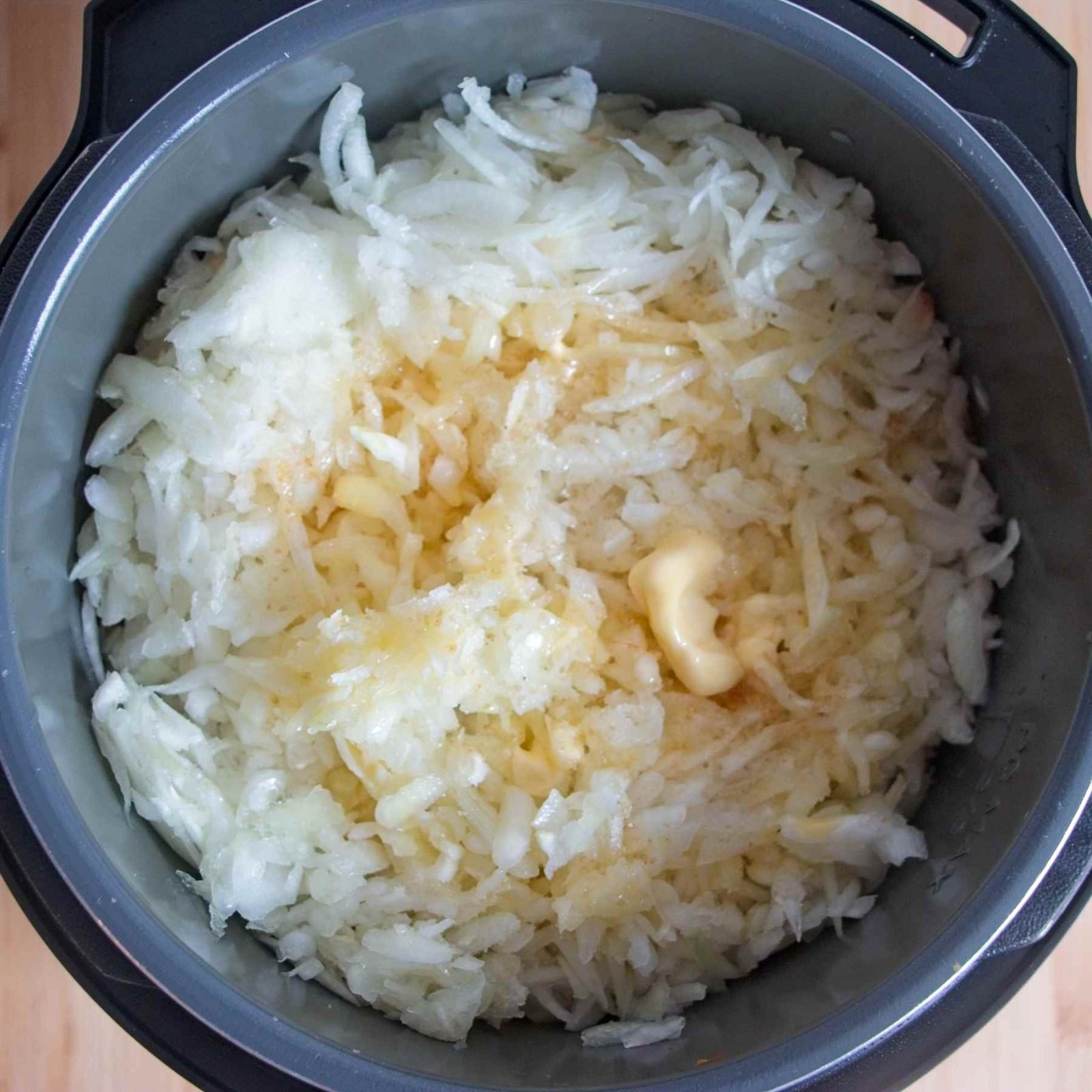 Sliced onions and butter added to an Instant Pot before slow cooking begins.
