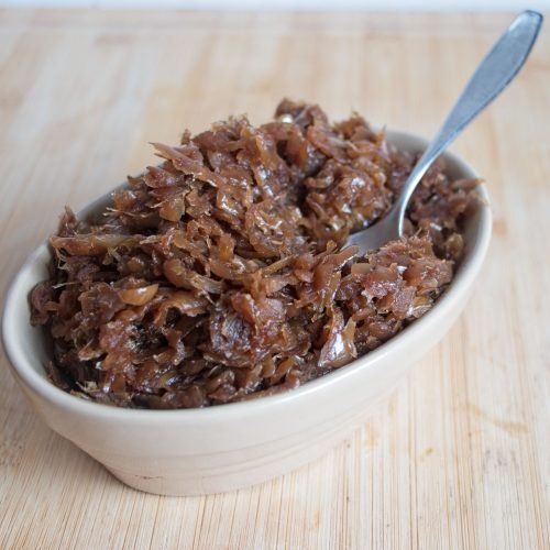 Slow cooker caramelised onions served in a bowl, deeply browned and glossy after the final high-heat stage.