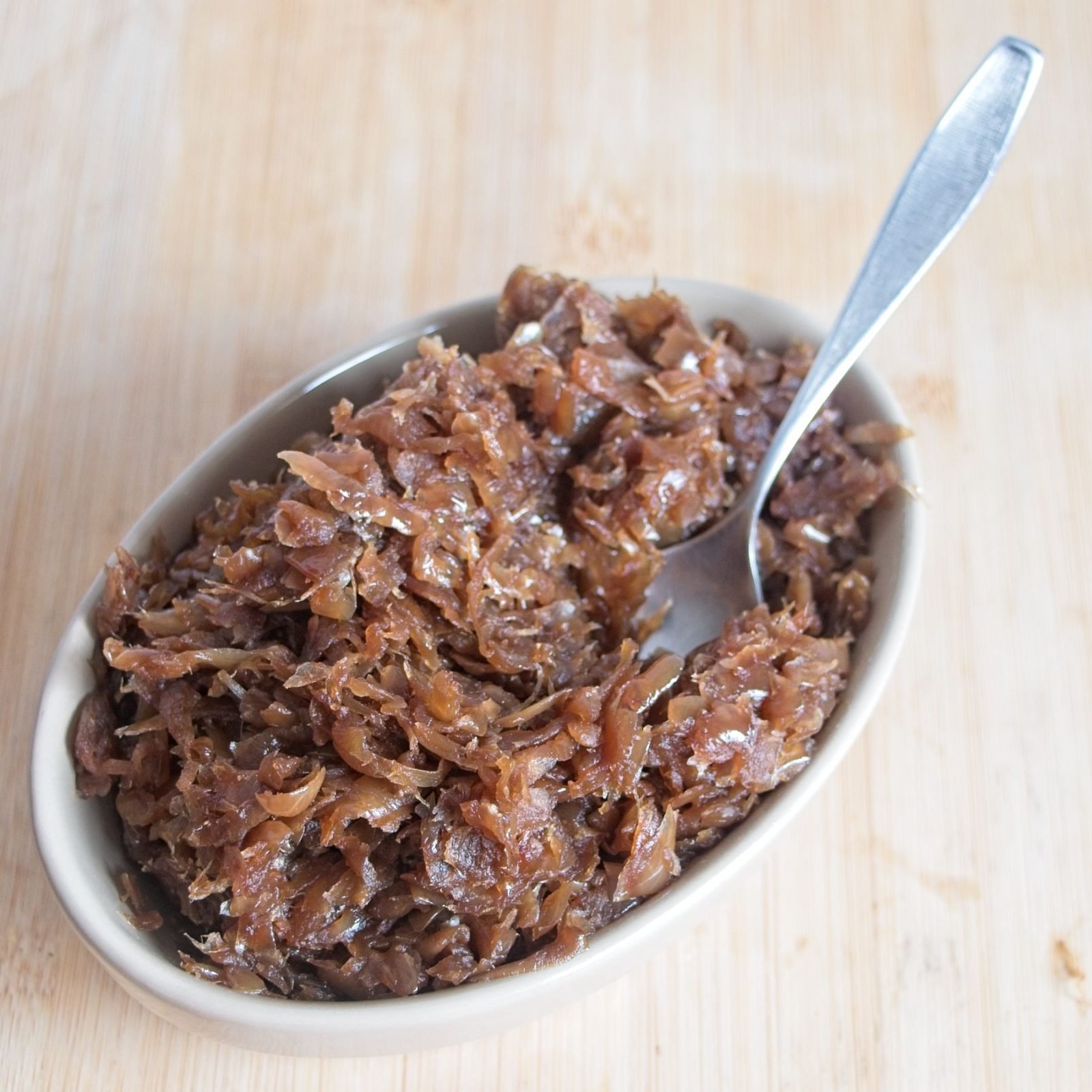 Bowl of slow cooker caramelised onions, finished over high heat until dark, glossy, and jam-like.