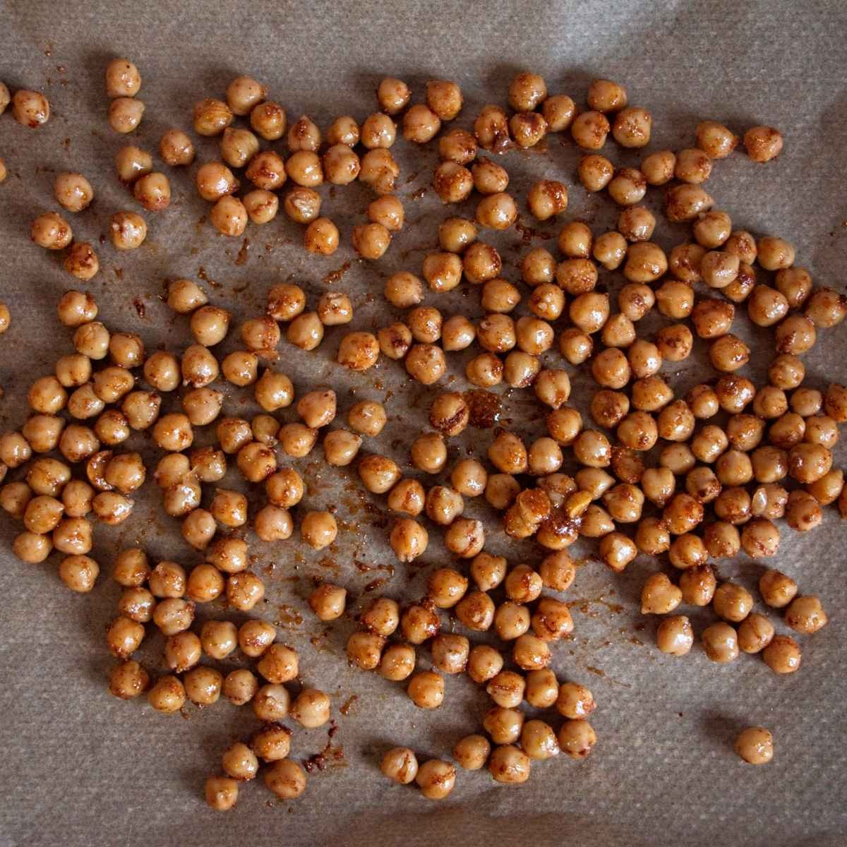 Spiced chickpeas spread on a parchment-lined baking tray before roasting.