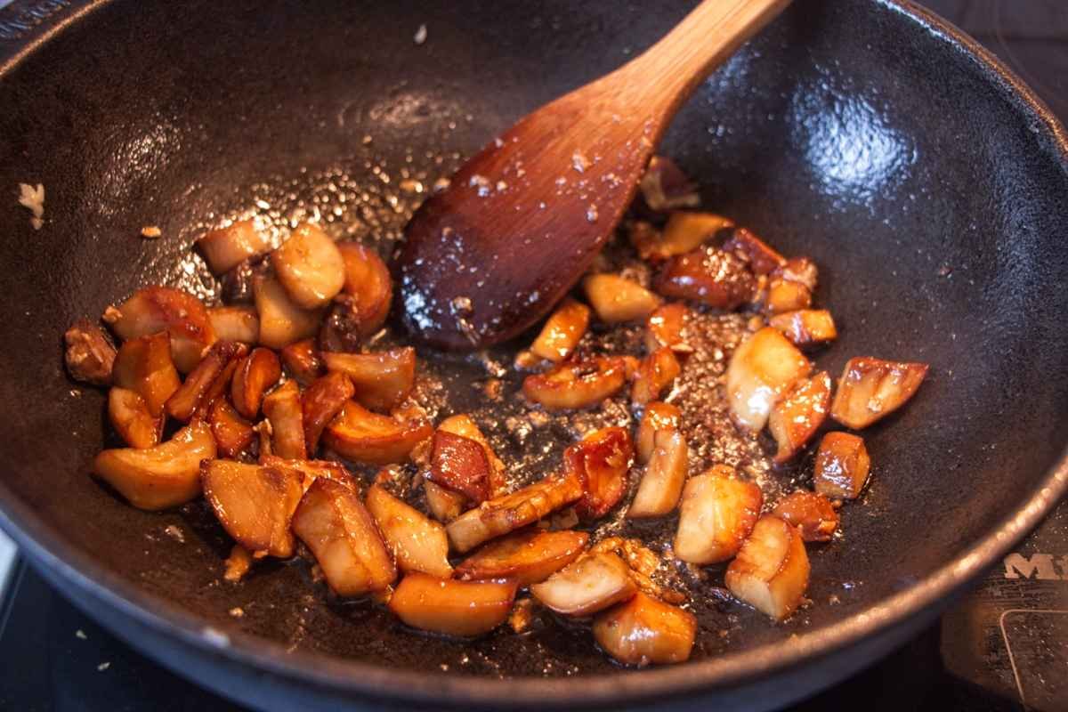 Sticky king oyster mushrooms being coated in a garlic soy miso glaze while cooking in a pan