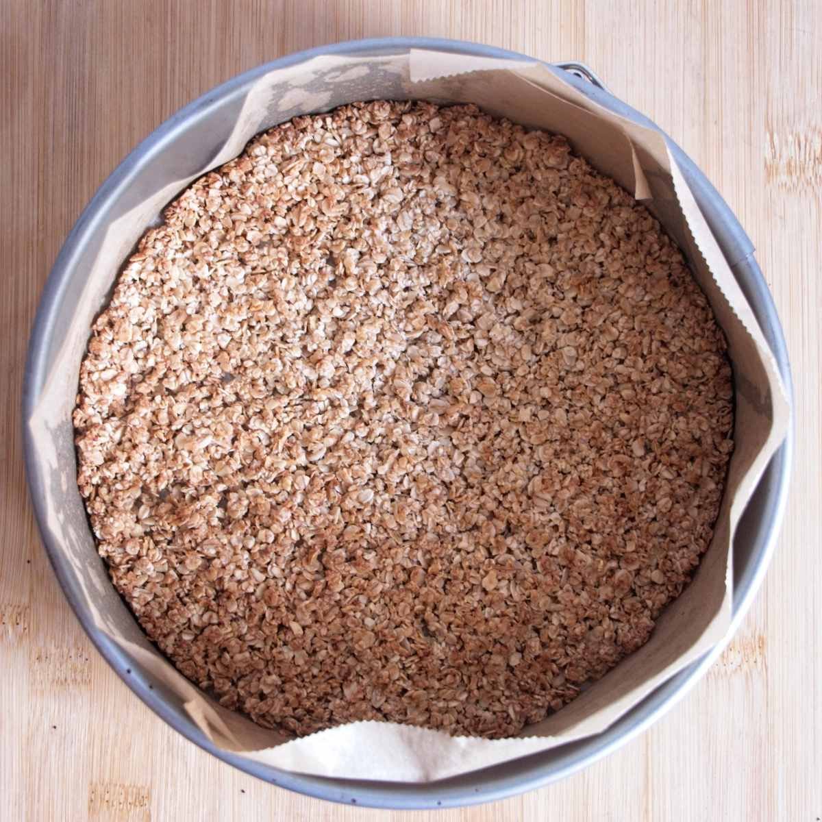 Baked oat cheesecake base set and lightly golden in a lined cake tin