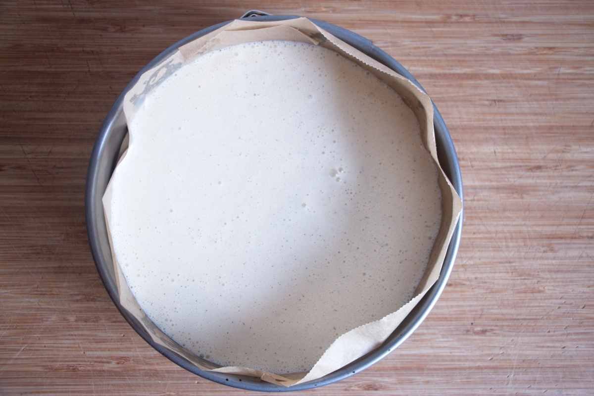 Smooth cheesecake filling poured over the oat base in a lined cake tin, ready to bake