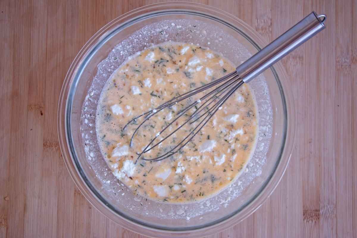 Finished cottage cheese muffin batter with herbs and feta in a glass bowl