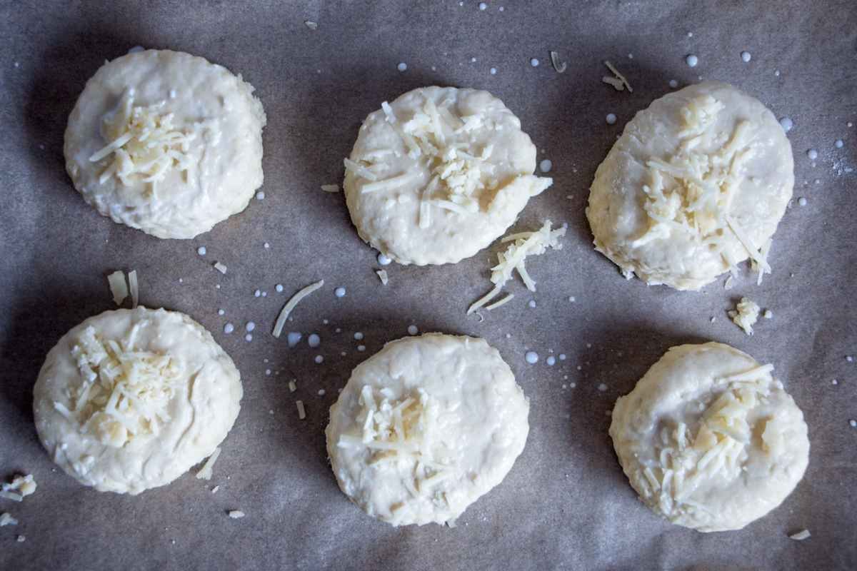 Unbaked cheese scones cut and arranged on a lined baking tray before baking