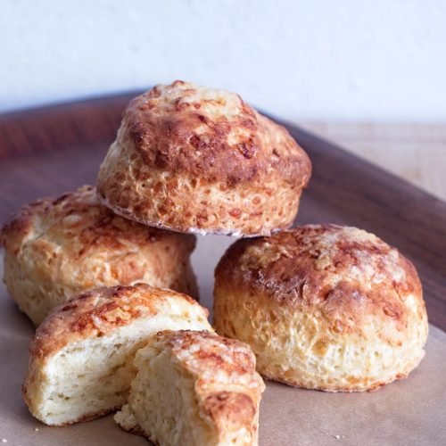 High protein scones stacked on baking paper with a split scone showing the soft interior