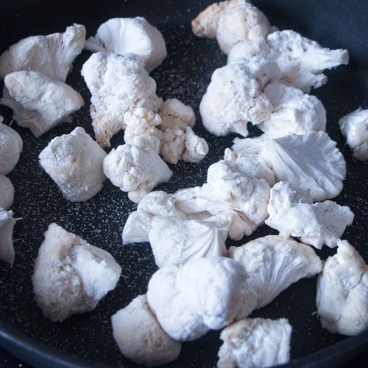 Lion’s mane mushroom pieces dry-cooking in a pan to release moisture