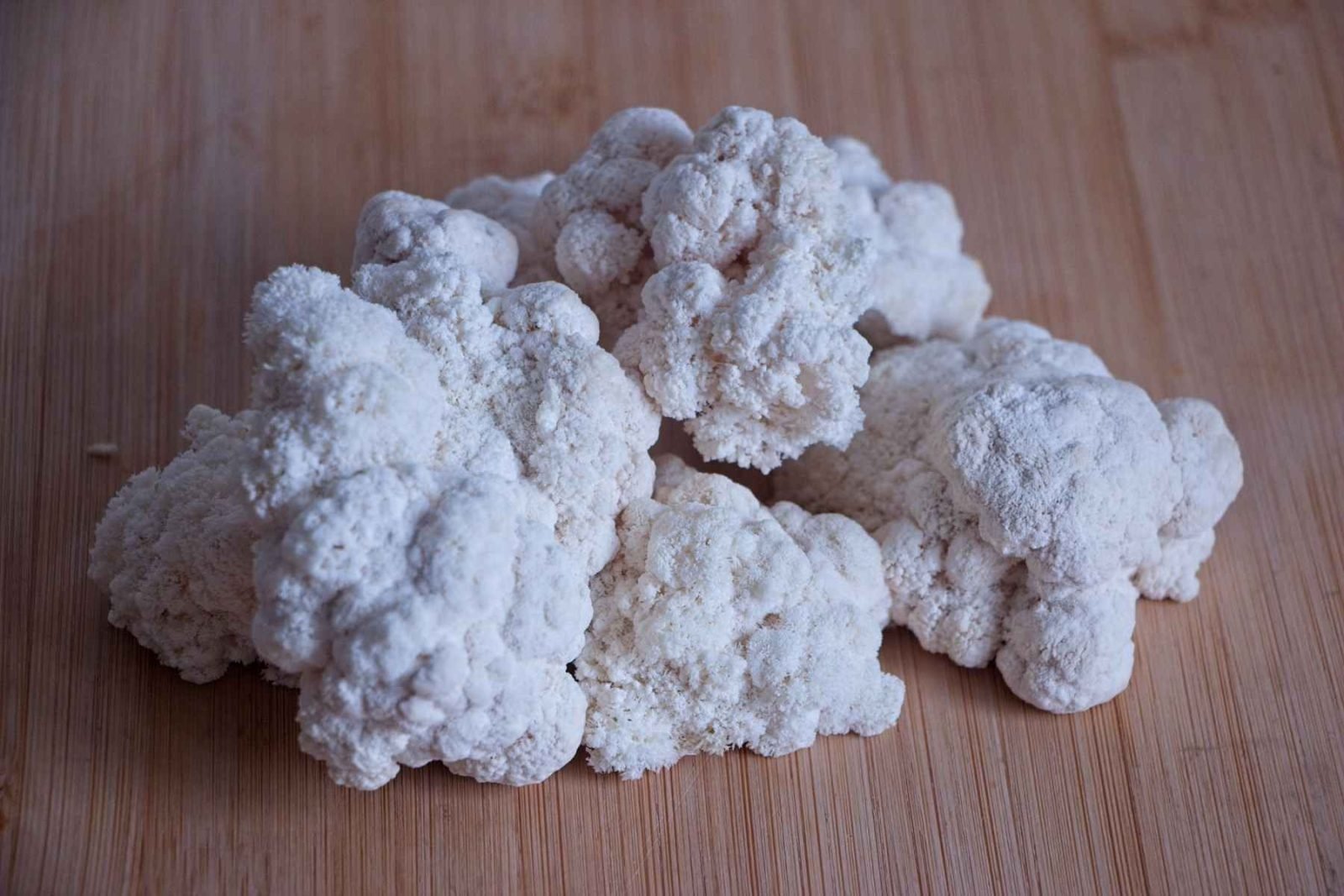 Raw lion’s mane mushroom florets arranged on a wooden board.