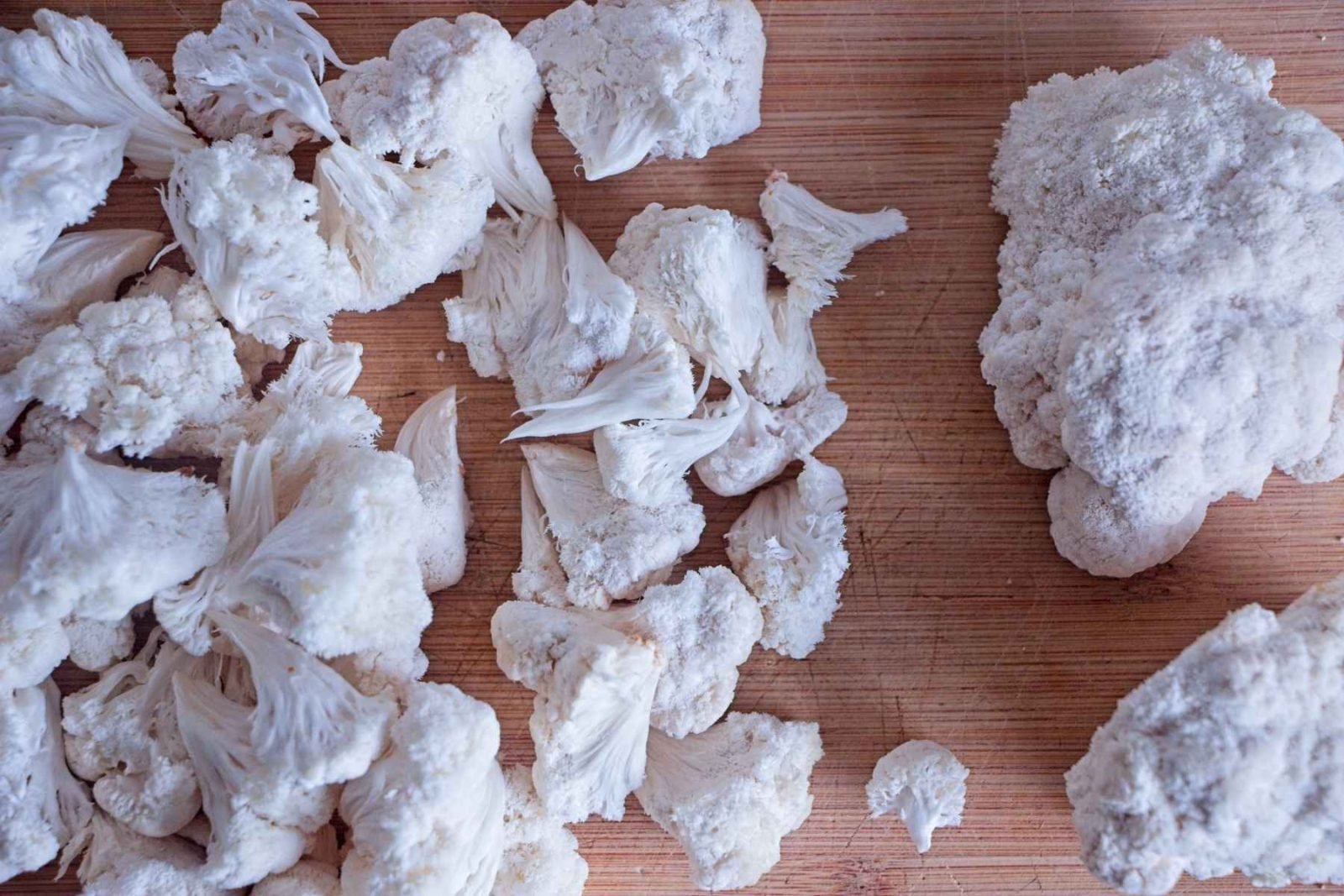 Lion’s mane mushrooms torn into chunks on a wooden board before cooking.