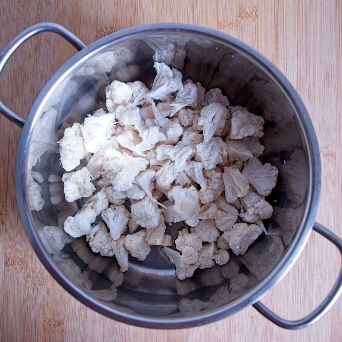 Lion’s mane mushrooms wilting in a saucepan after releasing their moisture.