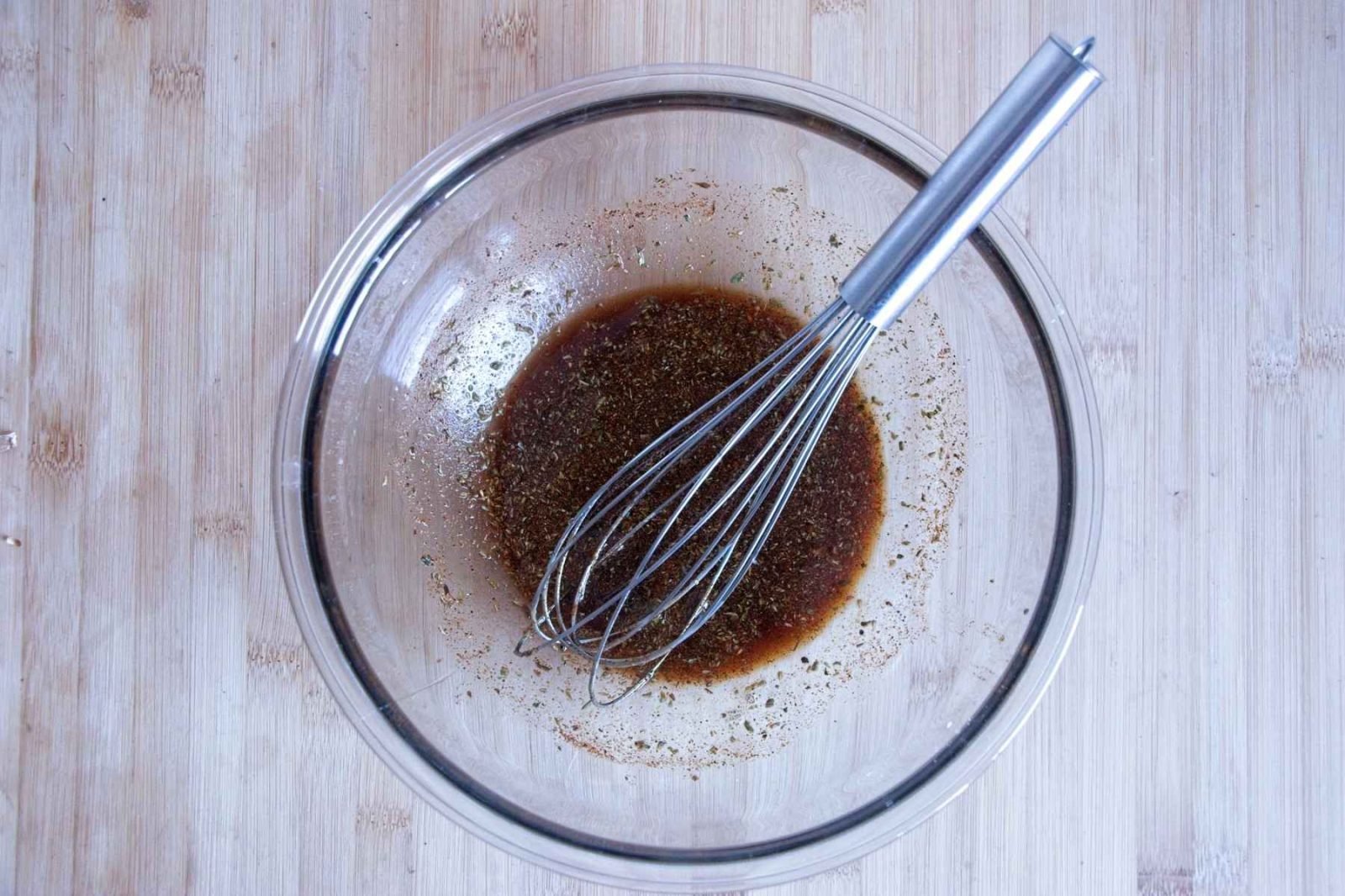 Soy-based marinade being whisked in a glass bowl, showing spices and seasoning fully mixed before adding the mushrooms.