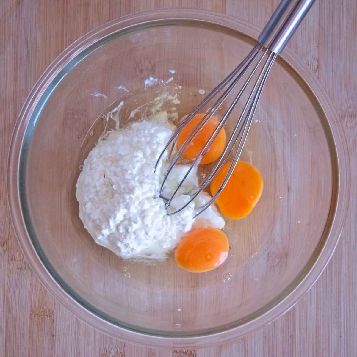 Eggs and cottage cheese in a glass bowl before whisking