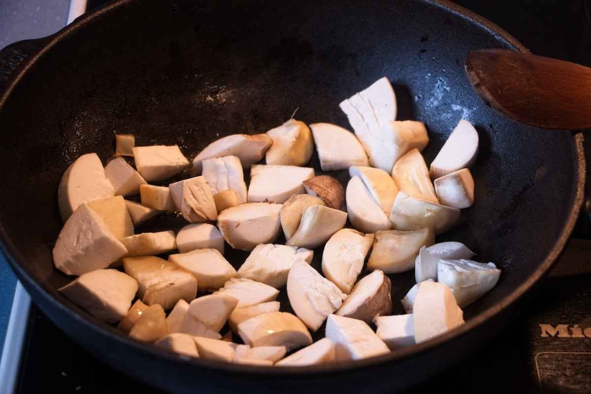 Chopped king oyster mushrooms frying in a pan before browning and glazing